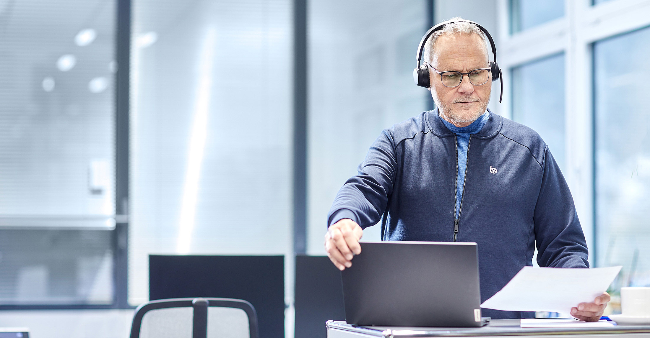 Mitarbeiter steht am Schreibtisch und schaut auf Laptop